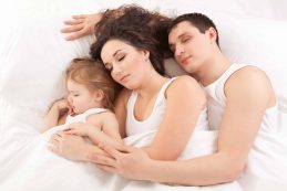 Happy,family,,mother,,father,and,daughter,resting,on,the,white