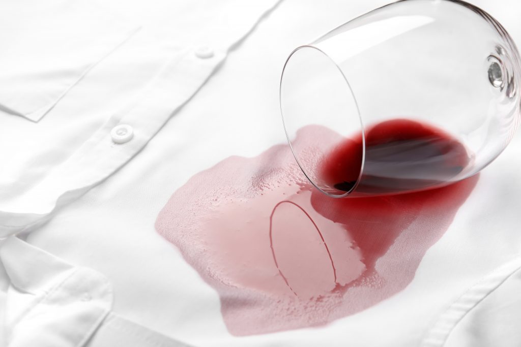Overturned,glass,and,spilled,exquisite,red,wine,on,white,shirt.