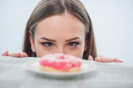 Beautiful,girl,is,looking,at,unhealthy,donut,with,appetite.,it