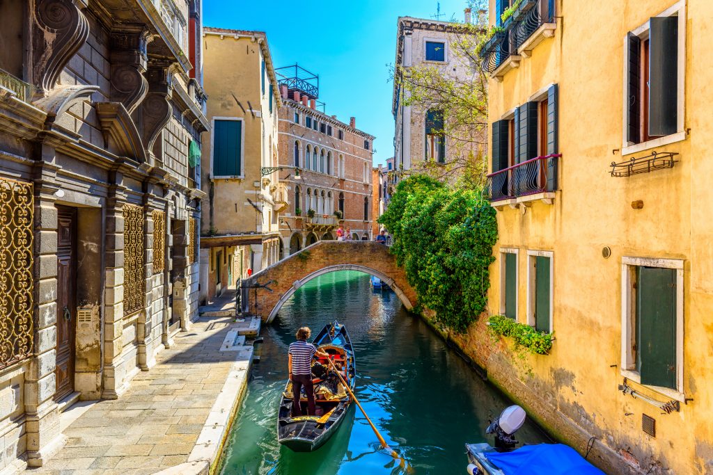 Narrow,canal,with,gondola,and,bridge,in,venice,,italy.,architecture