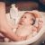 Small,baby,first,bathing,on,mothers,hands