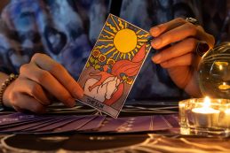 Fortune,teller,of,hands,holding,the,sun,card,and,tarot