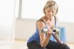 Fit,mature,woman,lifting,dumbbell,while,sitting,at,home