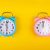 Two,alarm,clocks,on,a,bright,yellow,background,showing,different