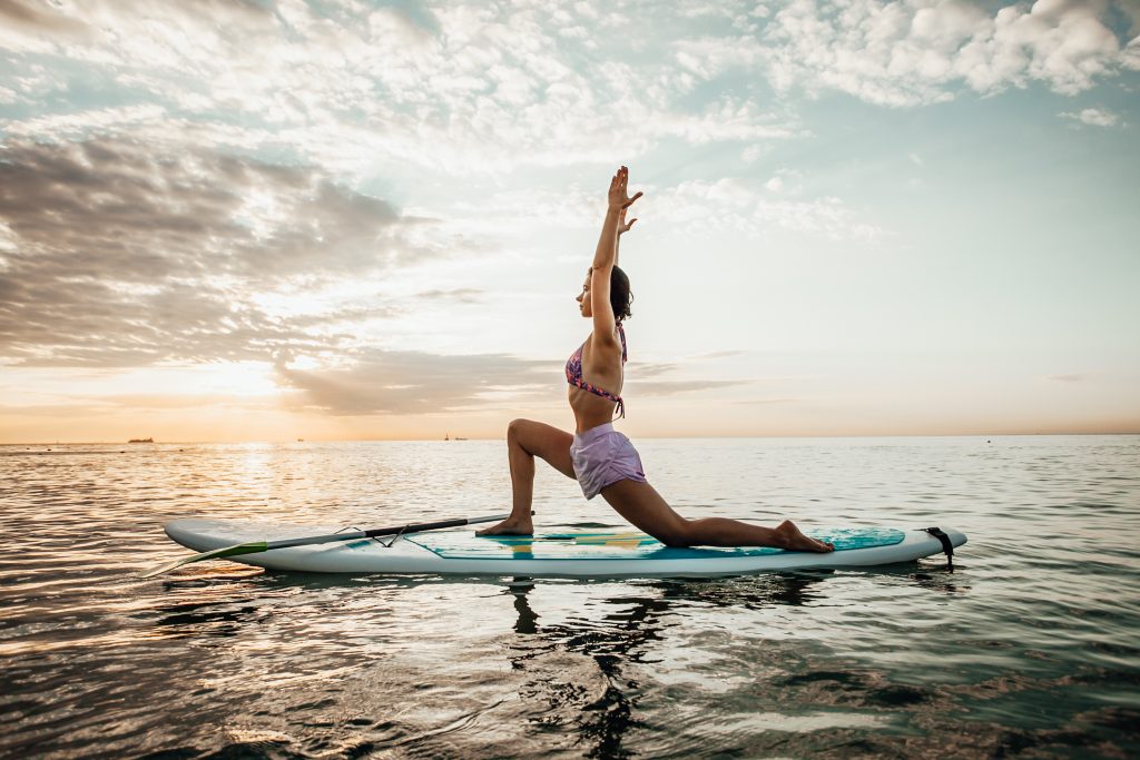 Young,woman,doing,yoga,on,a,sup,board,in,the