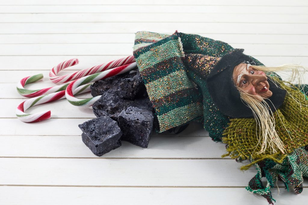 Befana,sock,with,sweet,coal,and,candy,on,wooden,background.