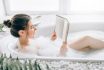Woman,lying,in,bath,with,foam,and,reads,magazine