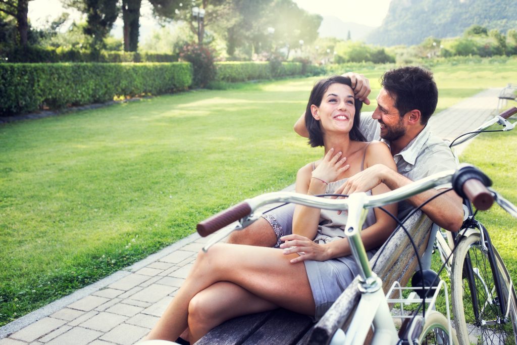 Couple,in,love,joking,together,on,a,bench,with,bikes