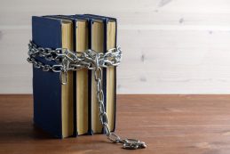 Chain,and,books,on,a,wooden,table,separating,a,light