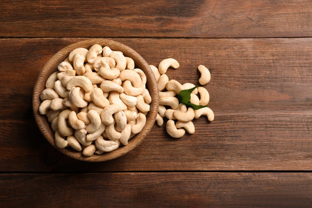 Tasty,cashew,nuts,in,bowl,on,wooden,table,,top,view.