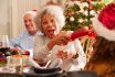 Grandmother,pulling,christmas,cracker,with,granddaughter,as,they,sit,for