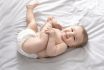 Beautiful Caucasian Baby Laying On Bed, Playing With Feet