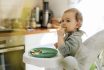 Cute Baby Girl Eating Meal At High Chair