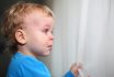 Little Boy Looking Through Window And Crying