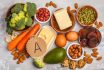 Healthy Food Nutrition Dieting Concept. Assortment Of High Vitamin A Sources. Carrots, Nuts, Broccoli, Butter, Cheese, Avocado, Apricots, Seeds, Eggs. White Background, Top View