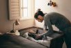 Young Mother Looking At Her Baby Sleeping In A Crib