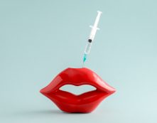 Red Lips And Syringe On Blue Background. Cosmetic Procedures , Lip Augmentation Concept.