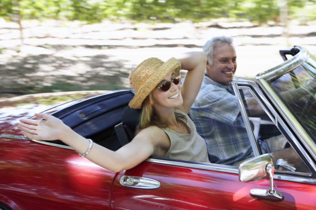 Young Woman And Mature Man Drive In A Convertible Car