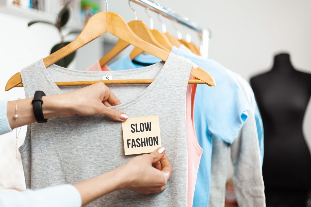 Slow Fashion. Clothes On Hangers In A Shop Showcase. Recycled Organic Apparel