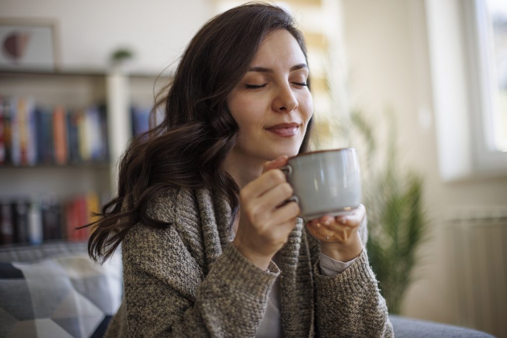 Young Smiling Woman Enjoying In Smell Of Fresh Coffee At Home