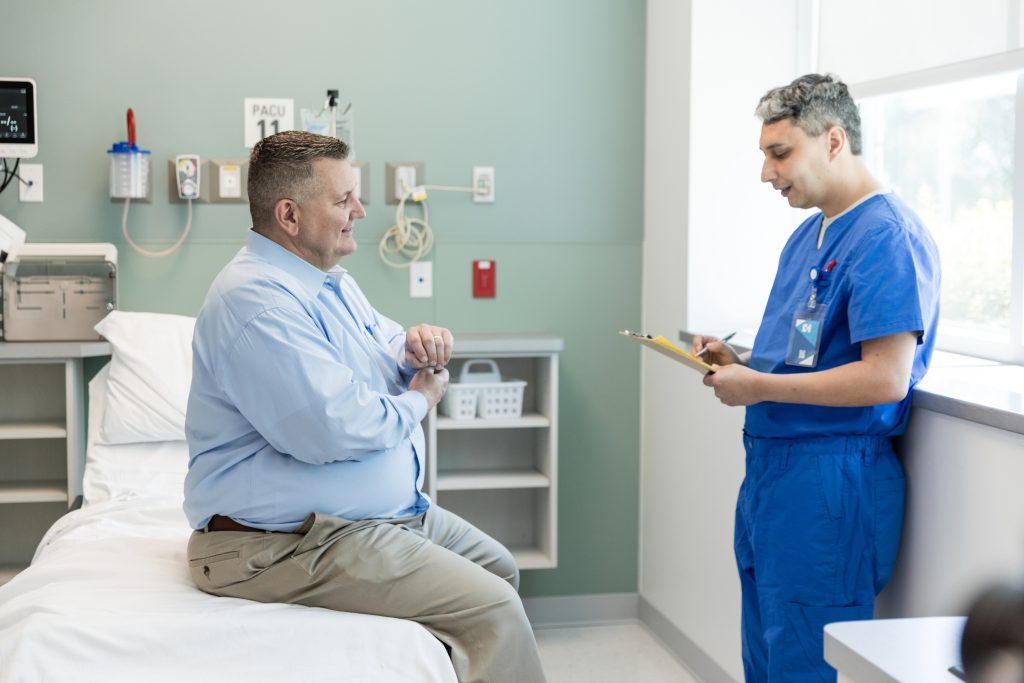 Male Patient Answers Questions From The Nurse Before Seeing The Doctor