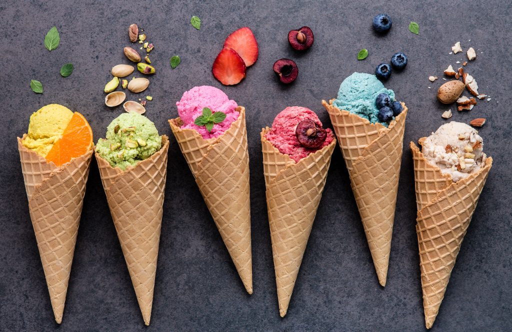 Various Of Ice Cream Flavor In Cones Blueberry ,strawberry ,pistachio ,almond ,orange And Cherry Setup On Dark Stone Background . Summer And Sweet Menu Concept.