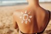 Skin Care. Sun Protection. Woman Apply Sun Cream. Woman With Suntan Lotion On Beach In Form Of The Sun. Portrait Of Female With Drawn Sun On A Shoulder. Suncream. Girl Holding Moisturizing Sunblock.