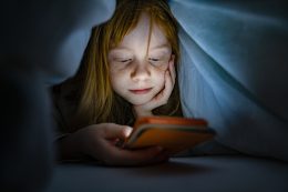 Girl Using Mobile Phone In Bed In The Dark