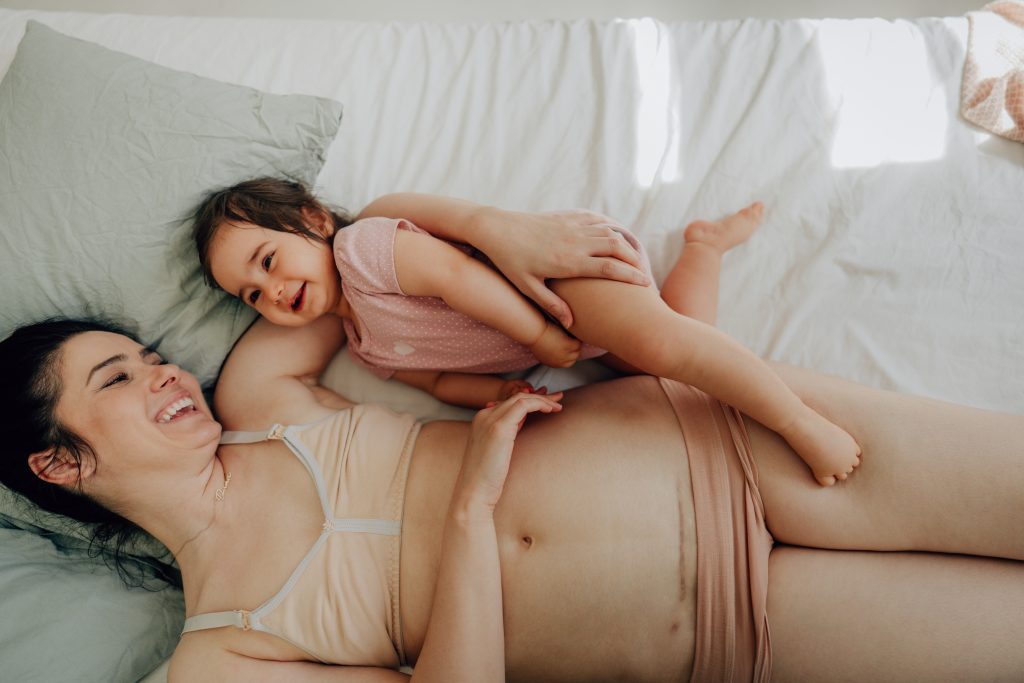 Mother With C Section Scar And Her Baby Lying On The Bed