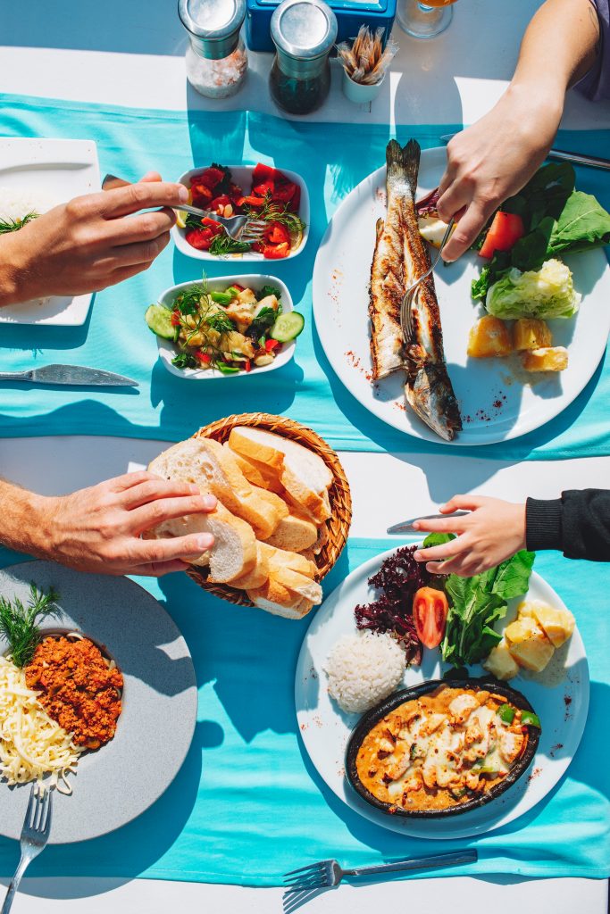 Top View Of Dinner Table With Fish, Salad, Bread, Spaghetti And Chicken