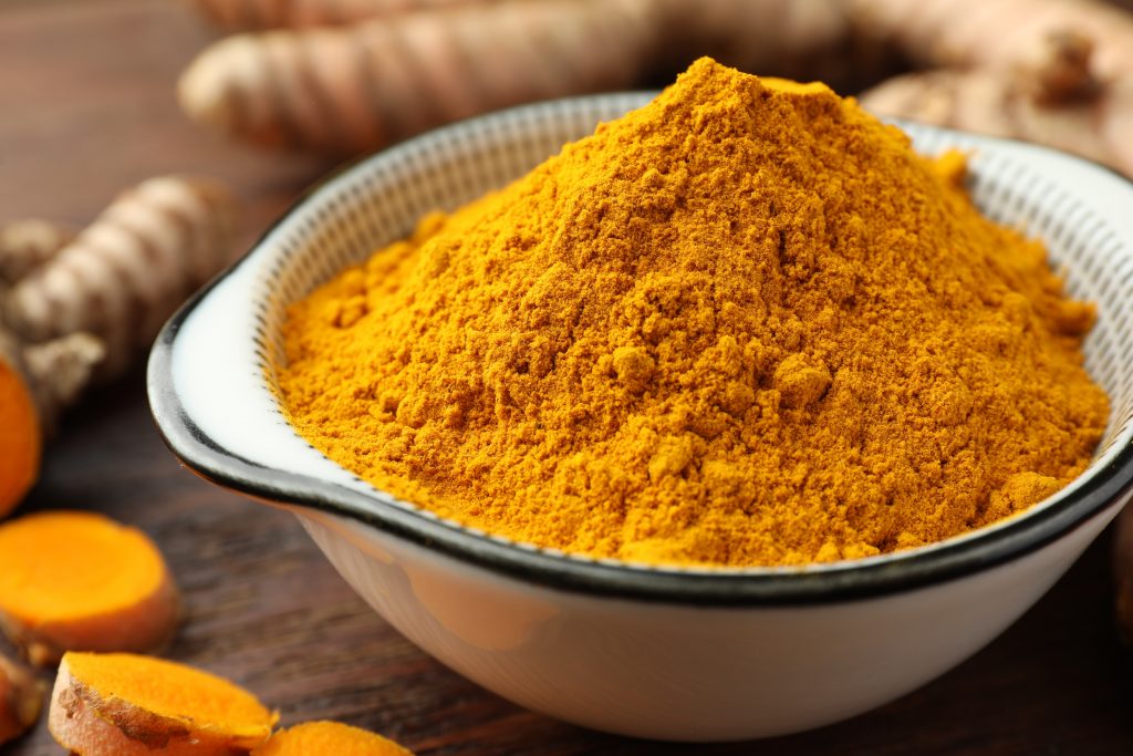 Bowl With Aromatic Turmeric Powder On Table, Closeup