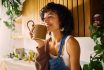 Content Woman Savoring The Aroma Of Her Morning Coffee In A Well Lit Kitchen With Modern Wooden Accents And Lush Houseplants, Embracing A Moment Of Serenity, Symbolizing Mindfulness And The Joy Of Simple Pleasures In Everyday Life