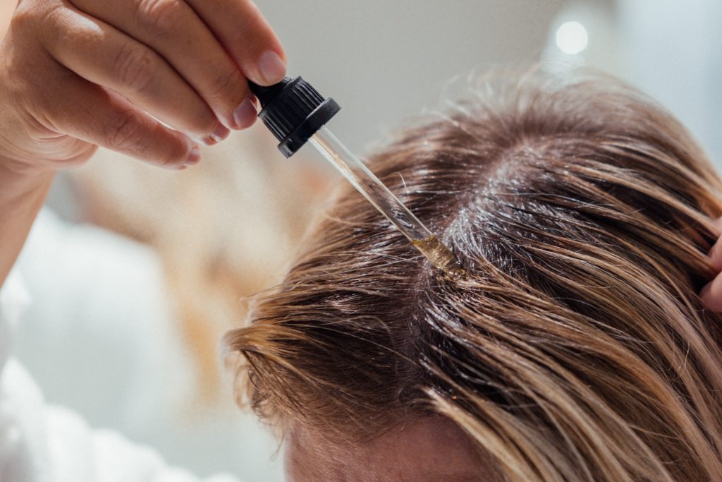 Woman Applies Oil To Her Hair With Pipette. Beauty Caring For Scalp And Hair.