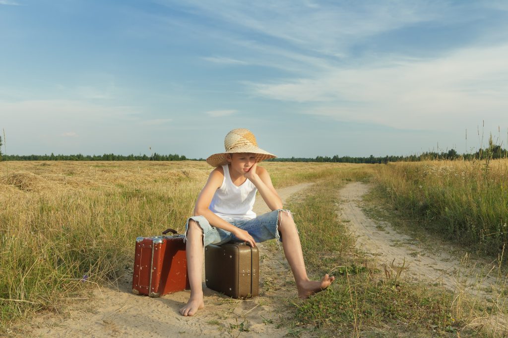 Teenage Traveler Waiting And Sitting On Luggage