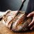 Woman Cutting Sourdough Bread With Knife On Board