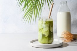 Iced Green Matcha Tea Mixed With Ice Cube And Milk In Latte Glass On White.