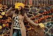 Happy Trendy Female In Beige Coat And Hat Against Stone Wall