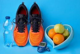 Orange Sneakers, Glucometer, Bottle Of Drinking Water And Fruits On Blue Background