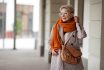 Smiling Woman Outdoor Portrait. Short Blonde Hair Fashion Model Wears Stylish Clothes, Double Breasted Jacket, Leather Handbag, Ochre Knitted Scarf And Glasses. Fashion Trend Of Autumn Or Spring