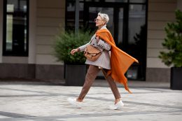 Confident Woman Walks Street, Wears Fashionable Clothes, Plaid Jacket, Pants, Leather Bag, Ochre Knitted Scarf, Loafers. Fashion Trend Of Autumn Or Spring