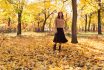 Positive Girl In Full Growth Walking In The Park In Autumn Among The Golden Maple Leaves. Foliage