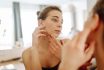 Close Up Of A Young Woman Looking At Pimples In The Mirror.