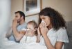 Parents, Girl And Bed With Tissue, Blowing Nose And Sick Together With Allergies, Flu Or Covid In House. Father, Mother And Daughter With Toilet Paper, Cleaning And Hygiene For Sneeze In Family Home