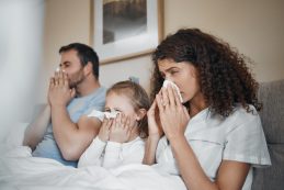 Parents, Girl And Bed With Tissue, Blowing Nose And Sick Together With Allergies, Flu Or Covid In House. Father, Mother And Daughter With Toilet Paper, Cleaning And Hygiene For Sneeze In Family Home