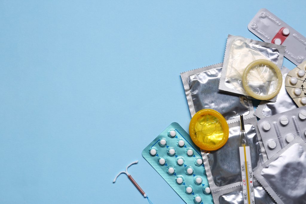 Contraceptive Pills, Condoms, Intrauterine Device And Thermometer On Light Blue Background, Flat Lay With Space For Text. Different Birth Control Methods