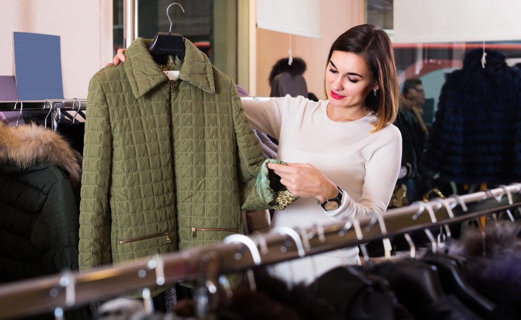 Woman Choosing Green Quilted Jacket In Womenâs Cloths Store