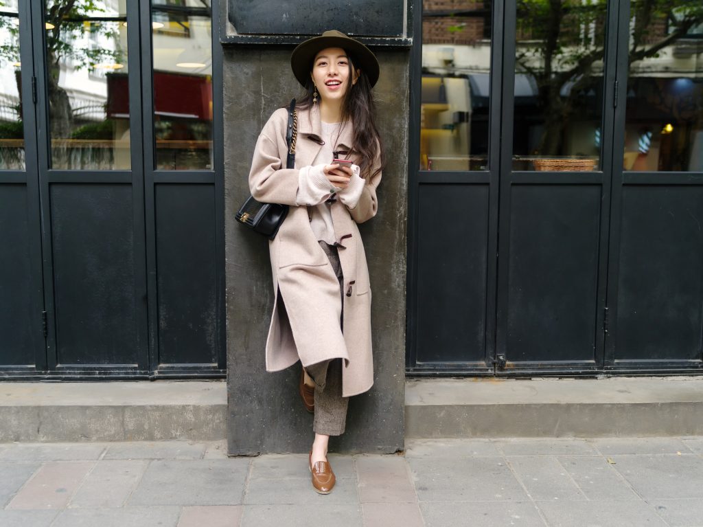 Beautiful Young Brunette Woman Wearing A Beige Coat In Autumn City. Outdoor Fashion Portrait Of Glamour Young Chinese Cheerful Stylish Lady In Street. Emotions, People, Beauty And Lifestyle Concept.