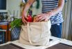 Asian Man Unpacking Groceries At Kitchen Island