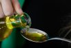 Pouring Oil From A Glass Bottle Onto A Spoon Close Up