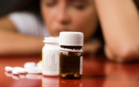 Pill Bottles With Pills Next To Them And A Woman In Back